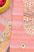 Close-up of Gota Patti work on peach Kota Doria fabric with golden motifs and green embellishments.