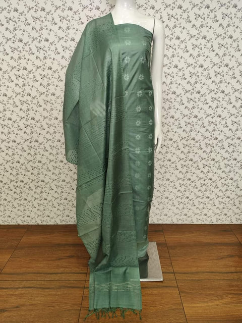 Semi Tussar Silk dress material in green with intricate woven designs, including top, dupatta, and plain bottom fabric. Lightweight and perfect for festive and casual occasions.