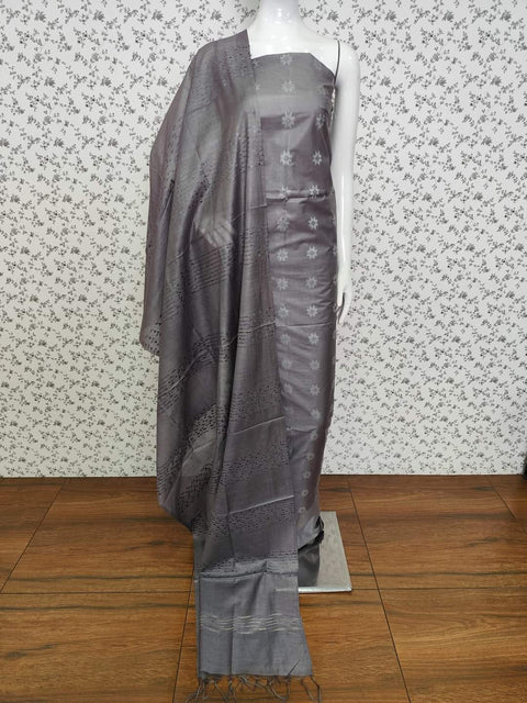 Grey Semi Tussar Silk dress material with delicate woven motifs, matching dupatta, and plain bottom fabric. Ideal for professional and festive occasions.