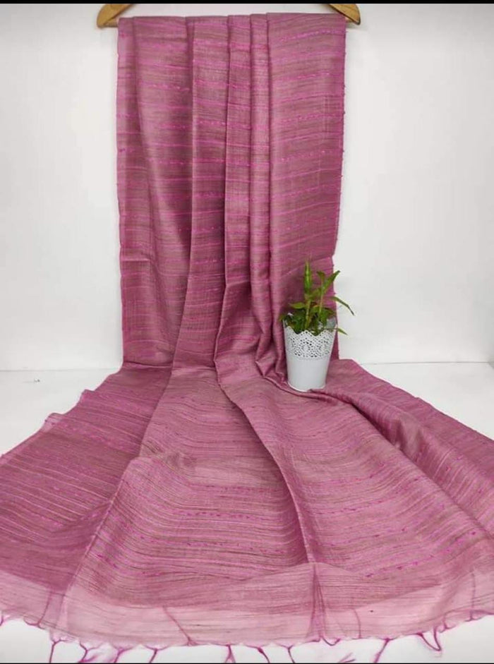Pink fabric draped over a white surface with a small plant in the foreground.