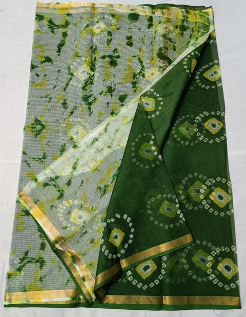 A green tie and dye print pure cotton Kota saree with a geometric pattern and a running unstitched blouse piece, displayed on a white background.